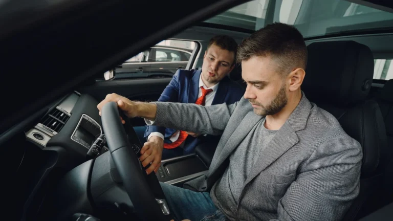Cliente prova un'auto in concessionaria con l'aiuto di un consulente per il noleggio a lungo termine