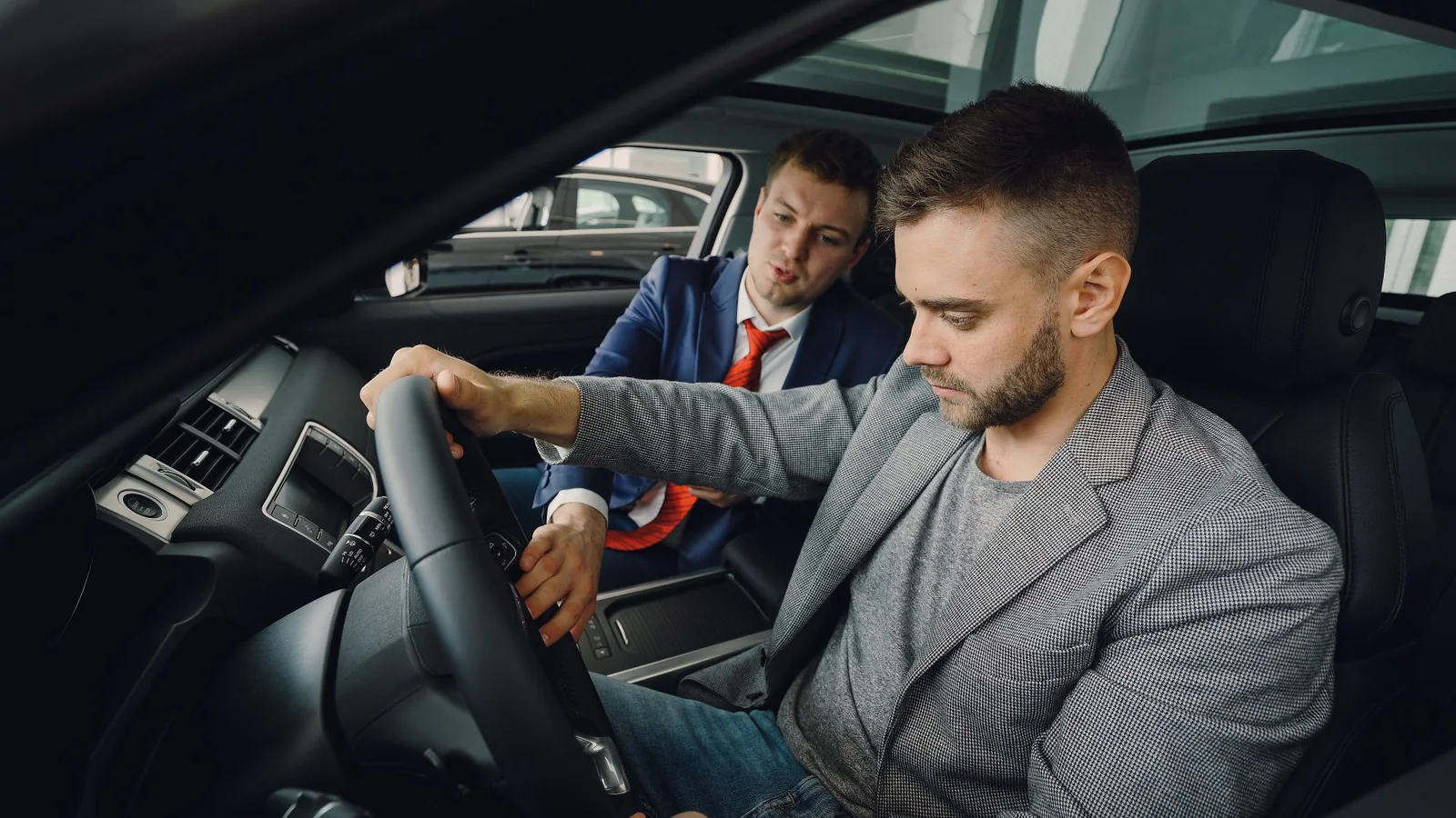 Cliente prova un'auto in concessionaria con l'aiuto di un consulente per il noleggio a lungo termine