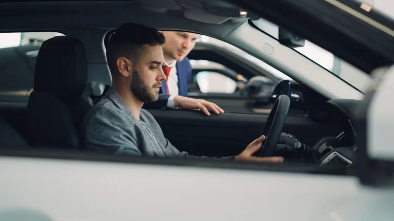 Consulente che spiega a un cliente al volante come funziona il noleggio a lungo termine